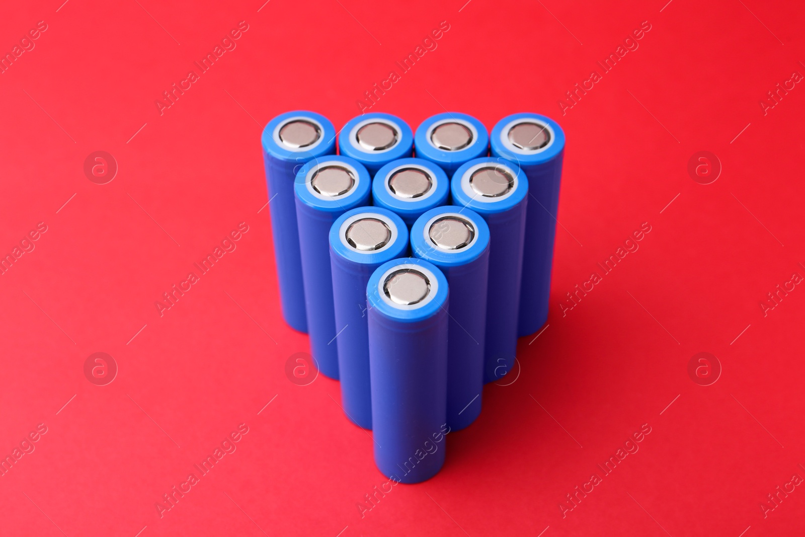 Photo of Many AA cell batteries on red background, closeup