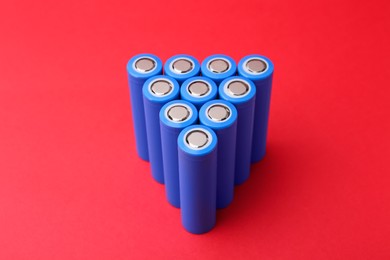 Photo of Many AA cell batteries on red background, closeup