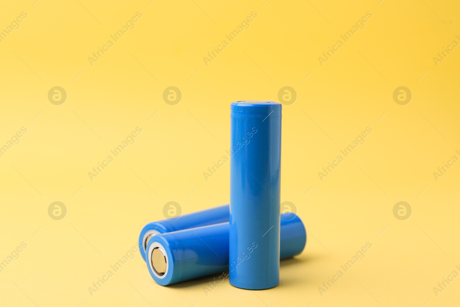 Photo of Three AA cell batteries on yellow background, closeup