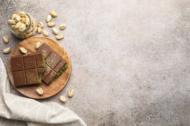 Photo of Pieces of Dubai chocolate bar with pistachios and knafeh on grey table, top view. Space for text