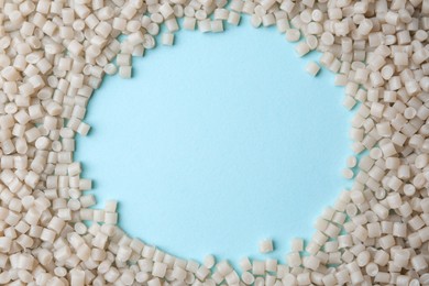 Frame of plastic granules on light blue background, top view. Space for text