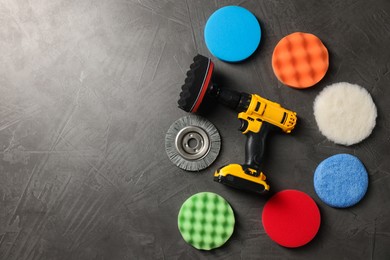 Photo of Electric screwdriver and polish pads on grey table, flat lay. Space for text