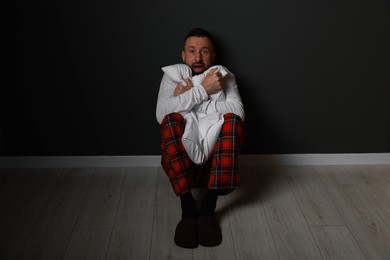 Photo of Fear of darkness. Scared man hugging pillow indoors at night