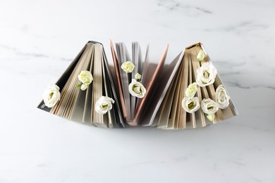 Books and beautiful eustoma flowers on white marble table, top view