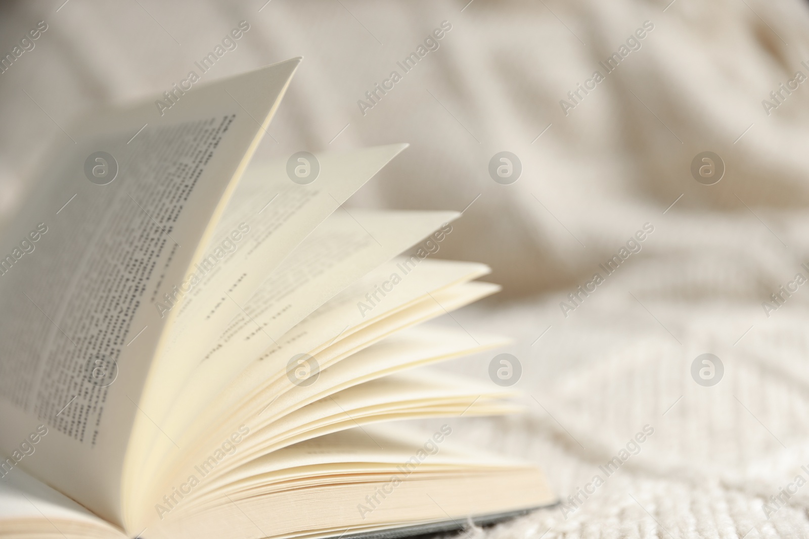 Photo of Open book on blanket, closeup. Space for text