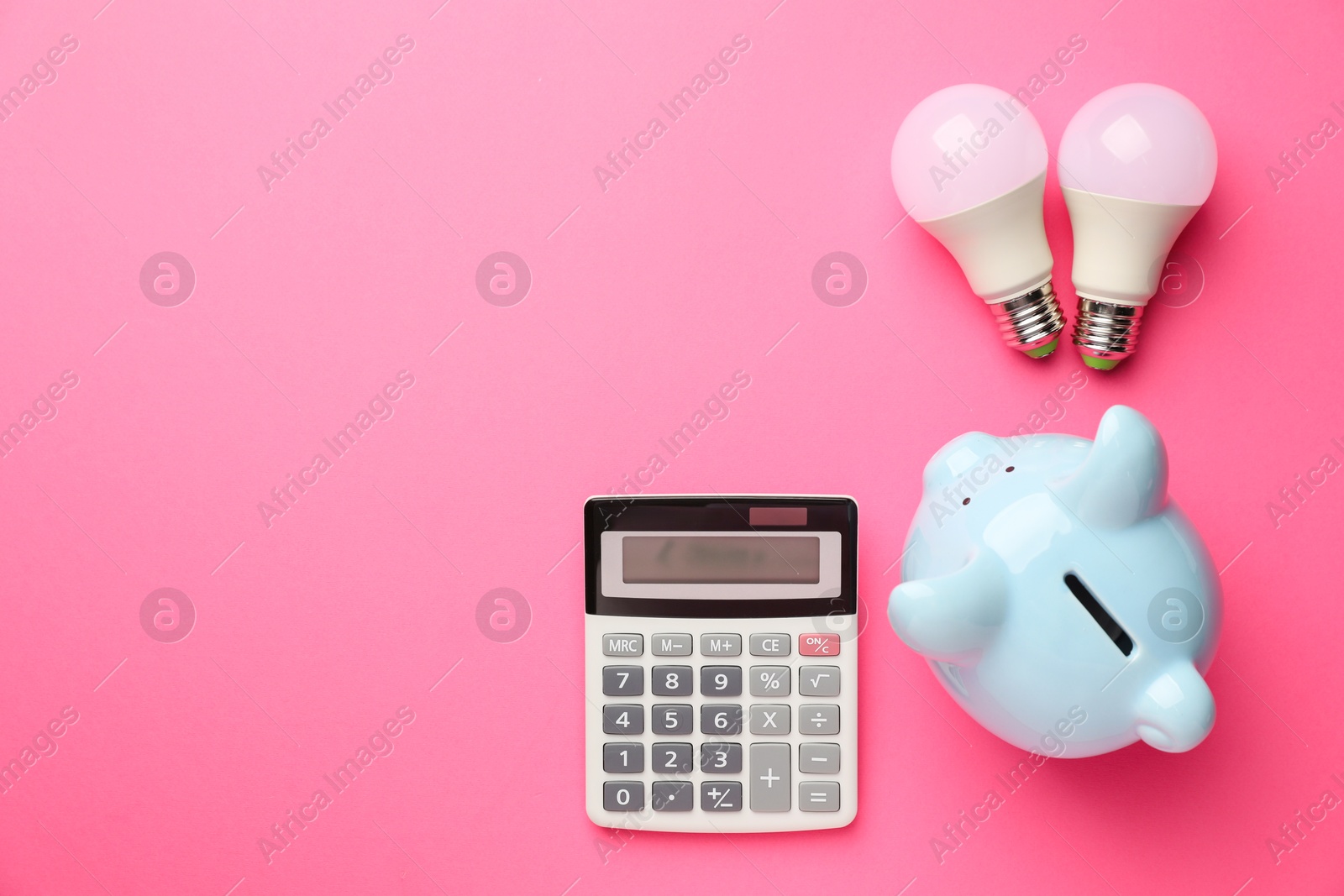 Photo of Piggy bank, calculator and light bulbs on pink background, flat lay with space for text. Energy saving concept