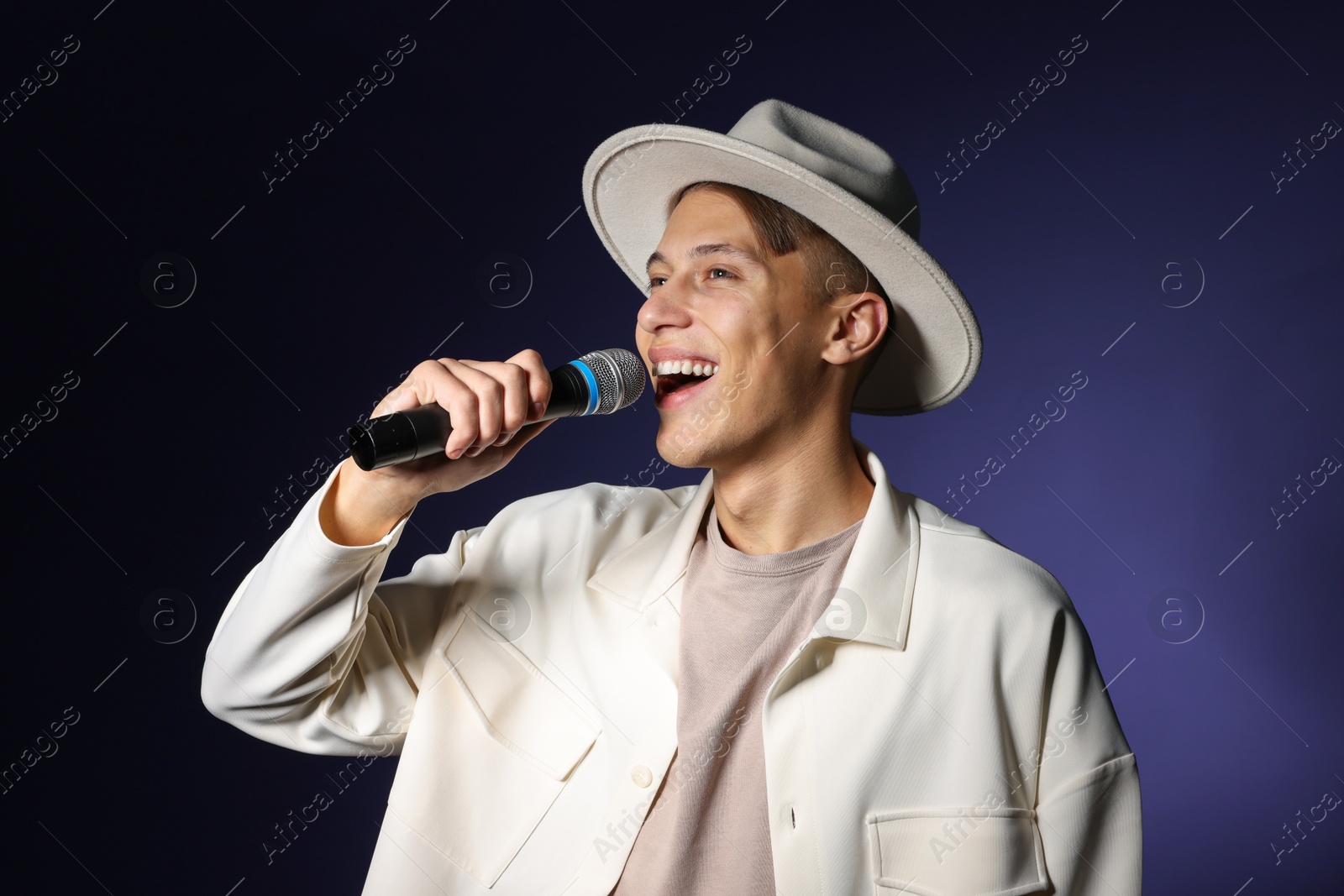 Photo of Talented young man singing on dark background