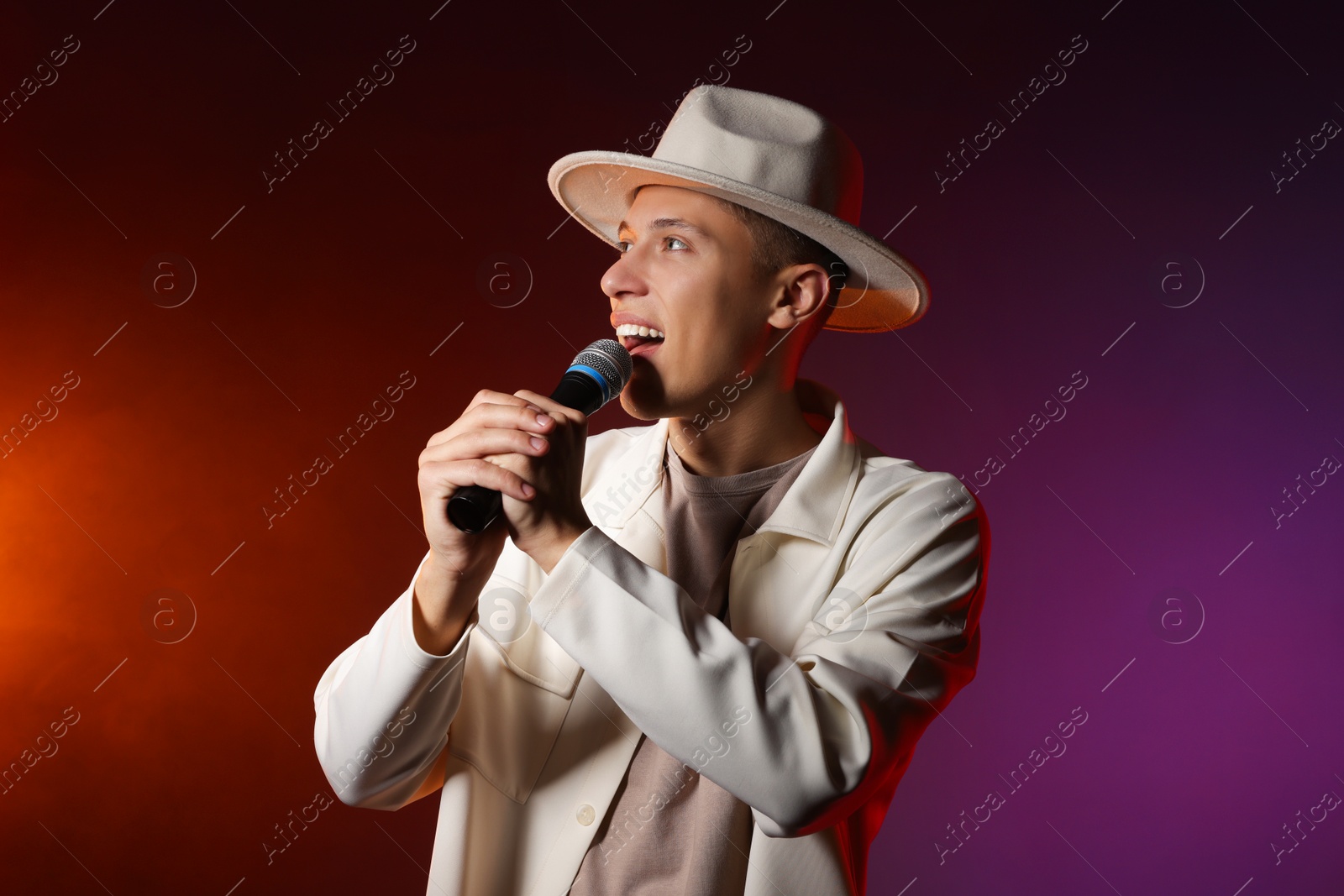 Photo of Talented singer performing on dark background with color lights