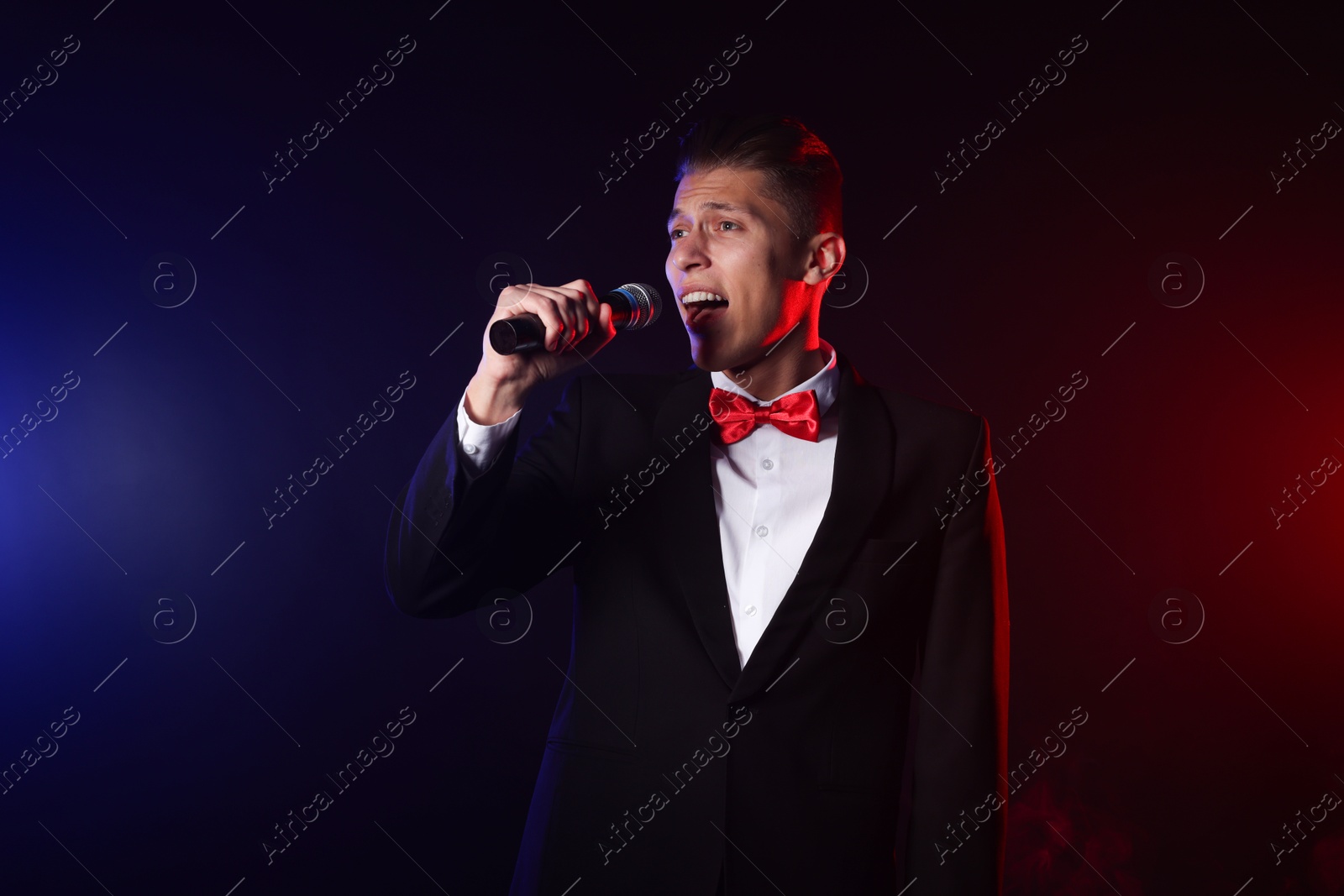 Photo of Talented singer performing on dark background with color lights