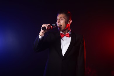 Photo of Talented singer performing on dark background with color lights