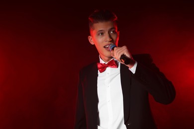 Photo of Talented singer performing on red background with smoke