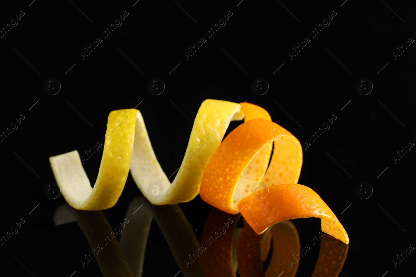 Photo of Lemon and orange peels on black mirror surface, closeup