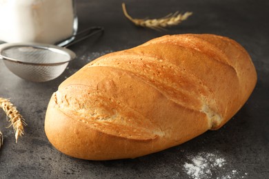 Photo of Freshly baked bread, spikes and sieve on grey table, closeup