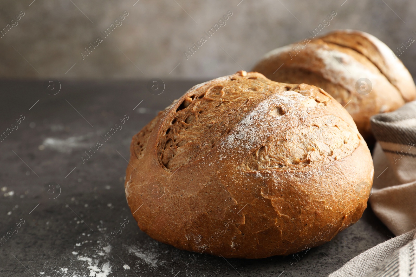 Photo of Freshly baked bread loafs on grey table, closeup. Space for text