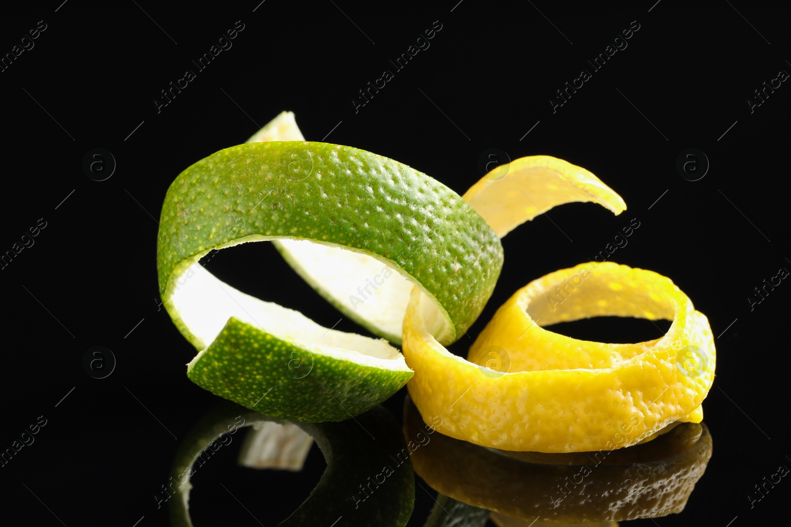 Photo of Lemon and lime peels on black glass surface, closeup