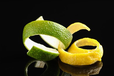 Photo of Lemon and lime peels on black glass surface, closeup