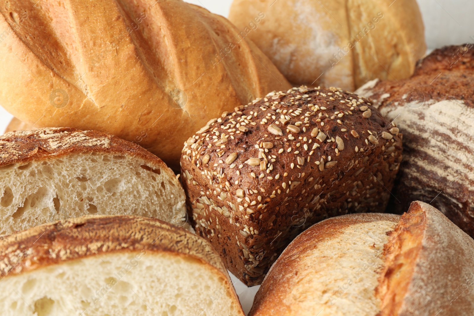 Photo of Whole and cut bread loafs on white table, closeup