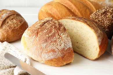 Photo of Cut loaf of freshly baked bread on white table, closeup