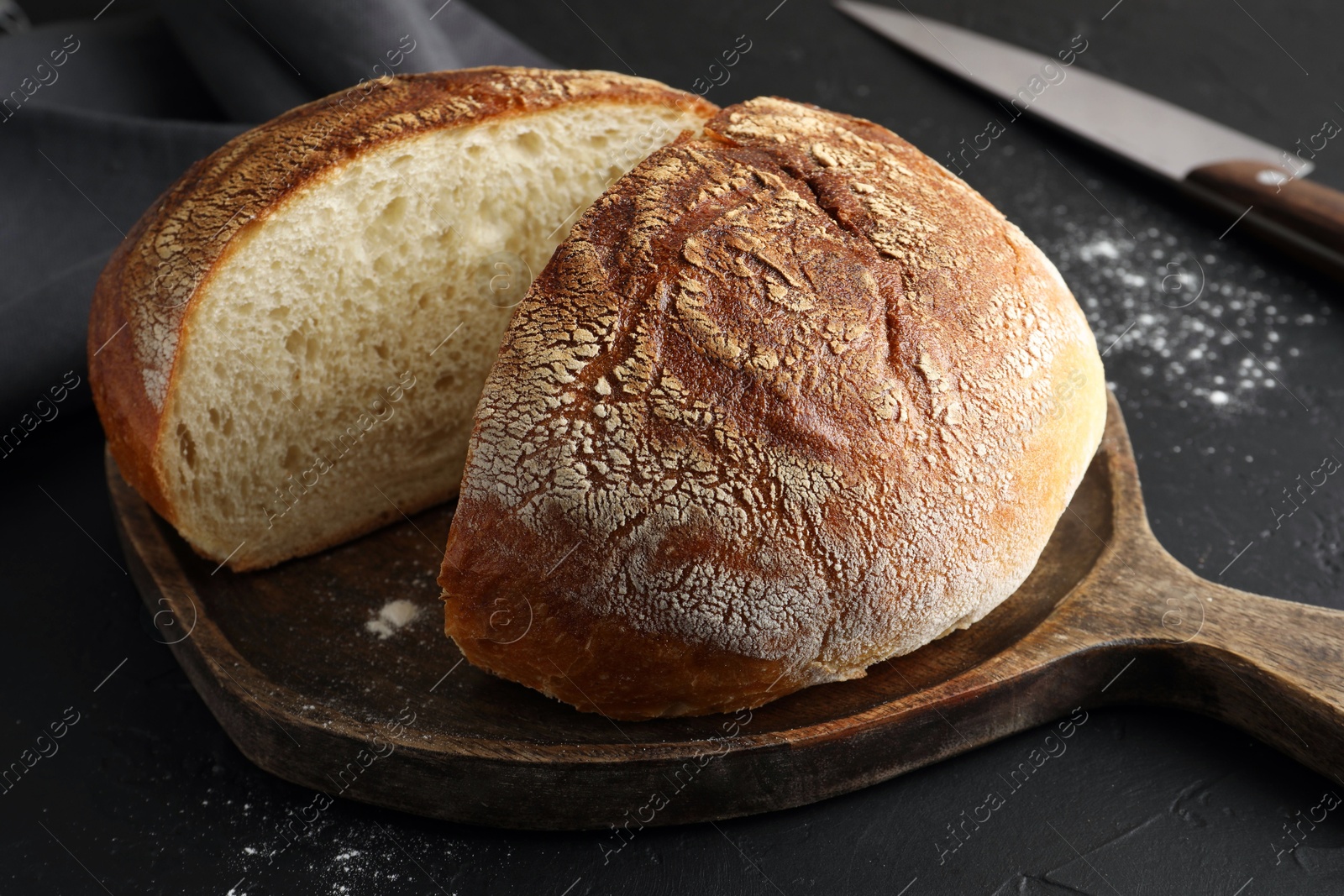 Photo of Cut loaf of bread on black table, closeup