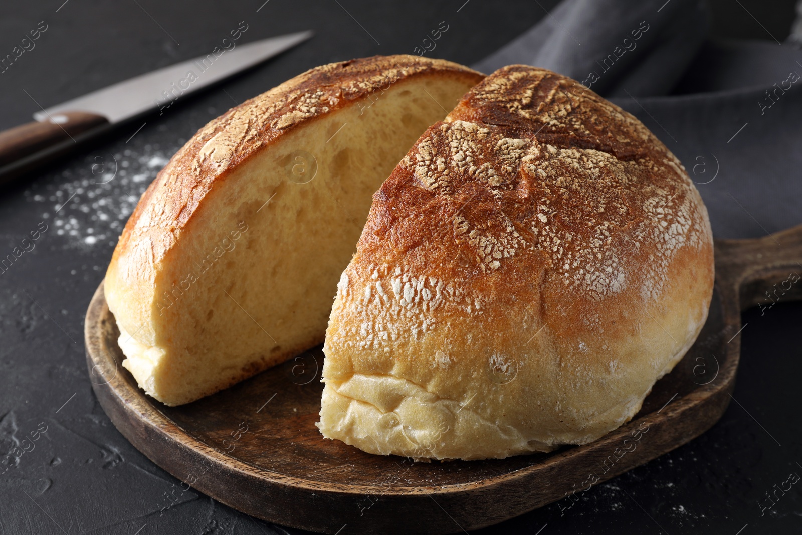 Photo of Cut loaf of bread on black table, closeup