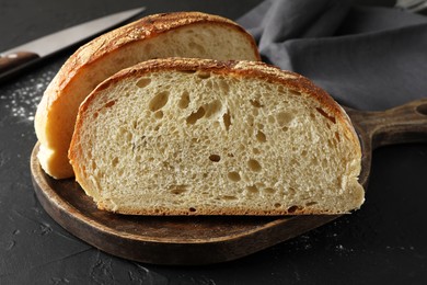 Photo of Pieces of fresh bread on black table, closeup