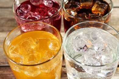 Photo of Soda water of different flavors with ice cubes in glasses on table, closeup