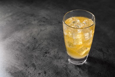 Photo of Sweet soda water with ice cubes in glass on grey table, space for text