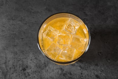 Photo of Sweet soda water with ice cubes in glass on grey table, top view