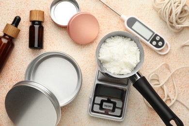 Photo of Soy wax, essential oils and different tools for making candles on beige textured table, flat lay