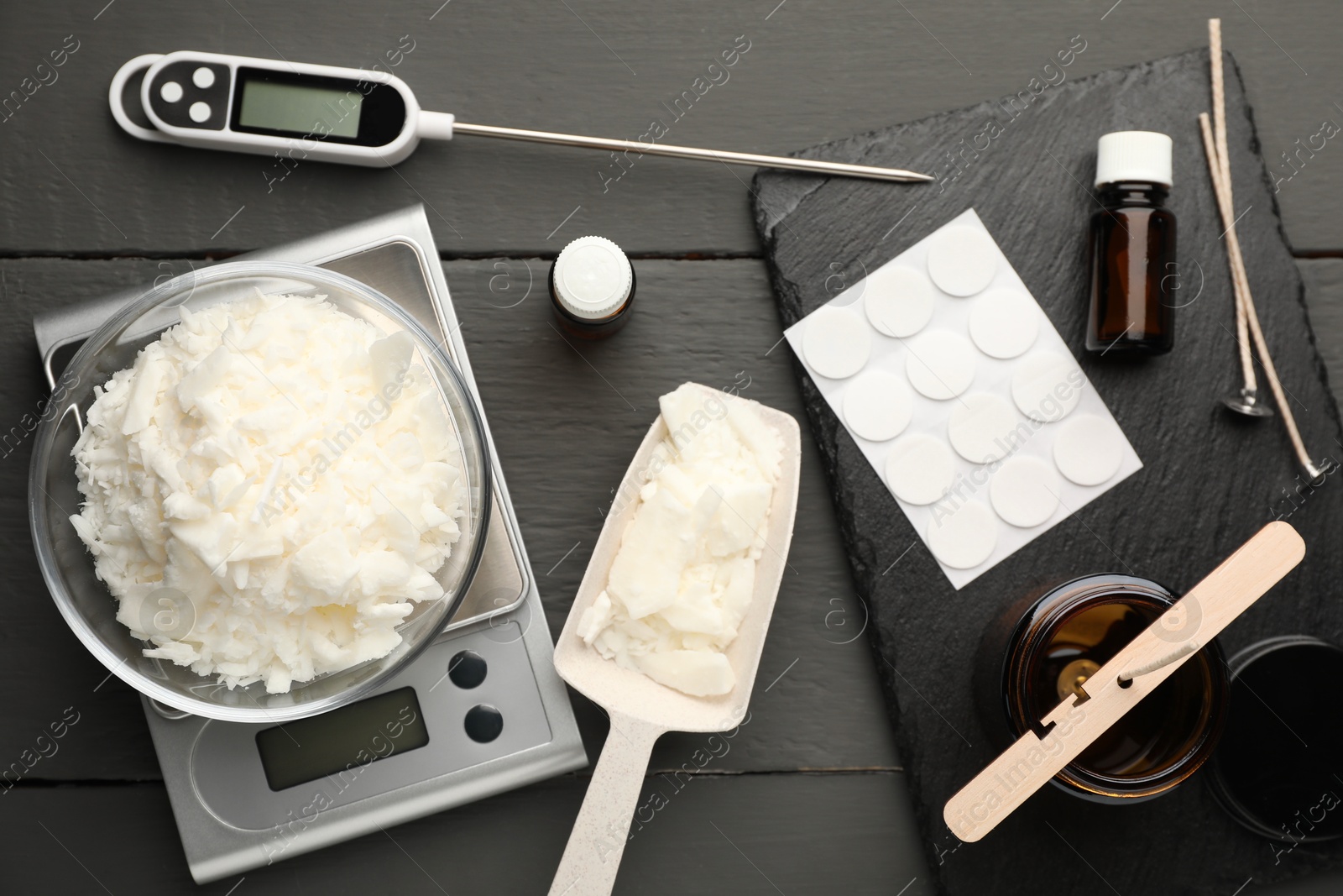 Photo of Soy wax, essential oils and different tools for making candles on grey wooden table, flat lay