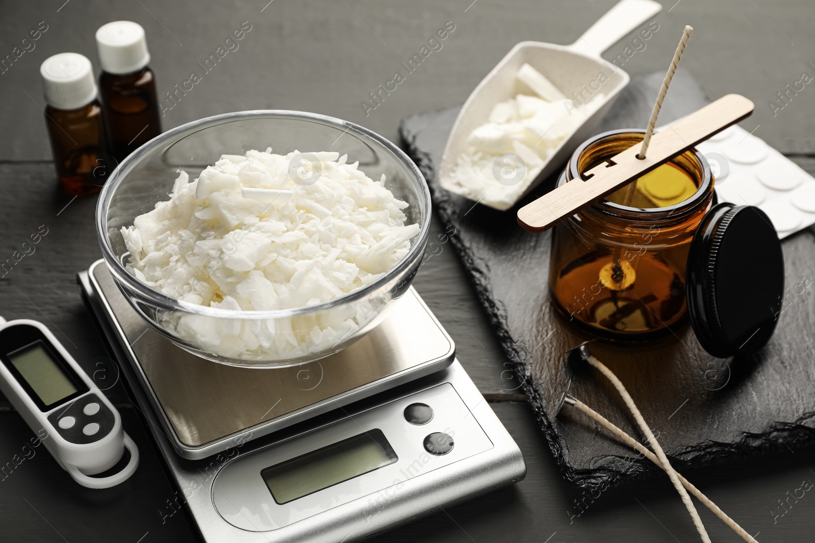 Photo of Soy wax, essential oils and different tools for making candles on grey wooden table, closeup