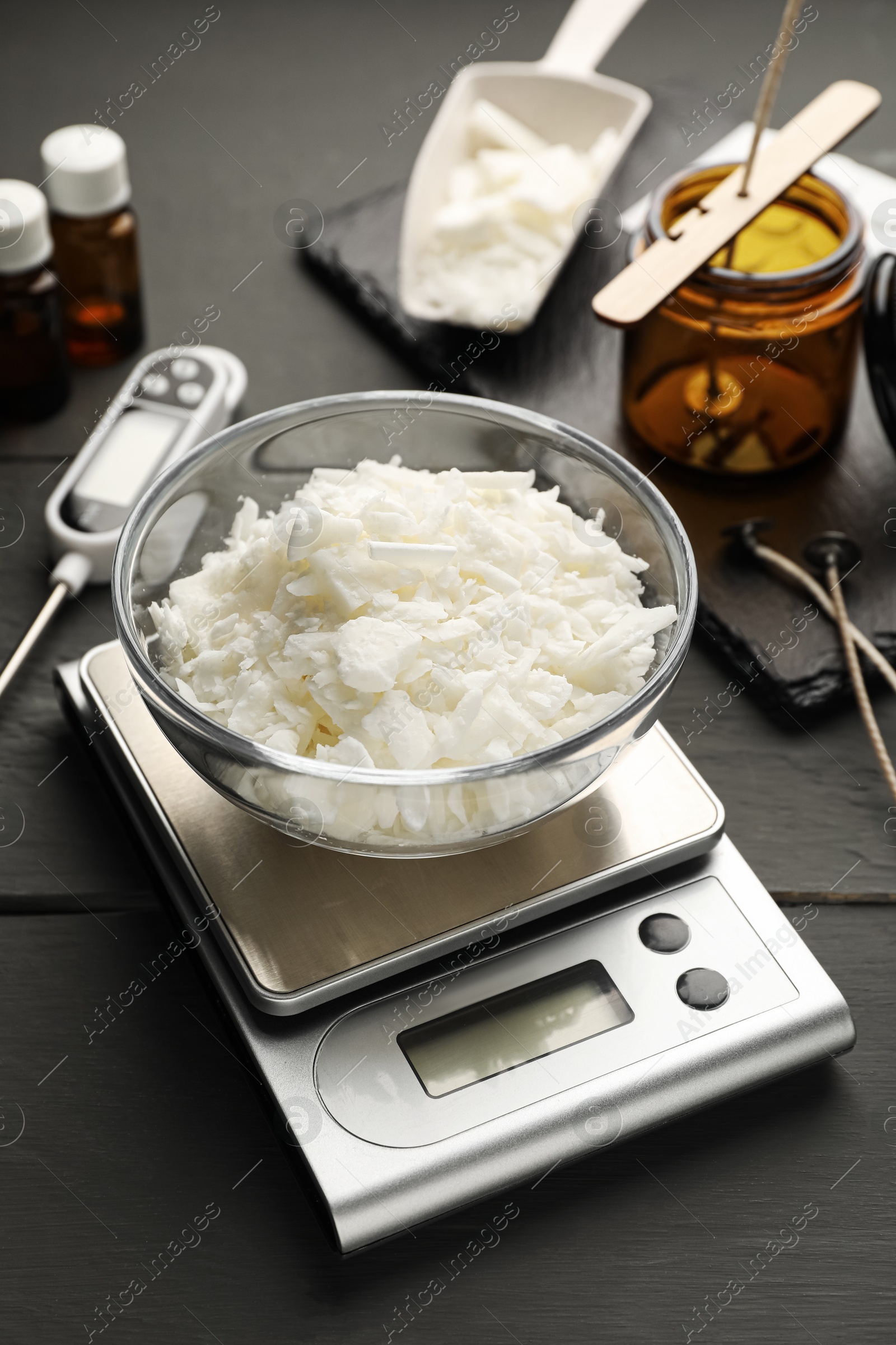 Photo of Soy wax, essential oils and different tools for making candles on grey wooden table, closeup