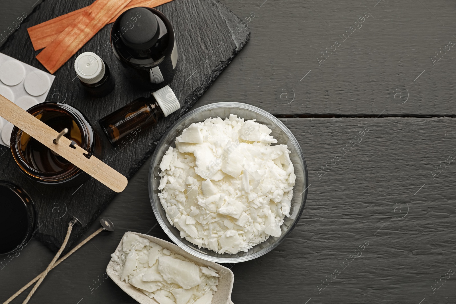 Photo of Soy wax, essential oils and different tools for making candles on grey wooden table, flat lay. Space for text