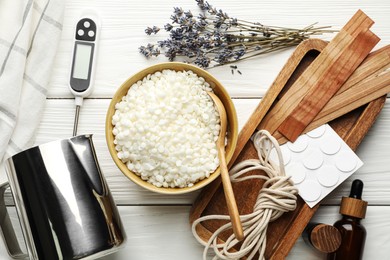 Photo of Soy wax in bowl, essential oils and different tools for making candles on white wooden table, flat lay