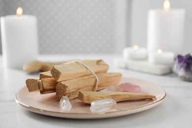 Photo of Palo santo sticks and gemstones on white table