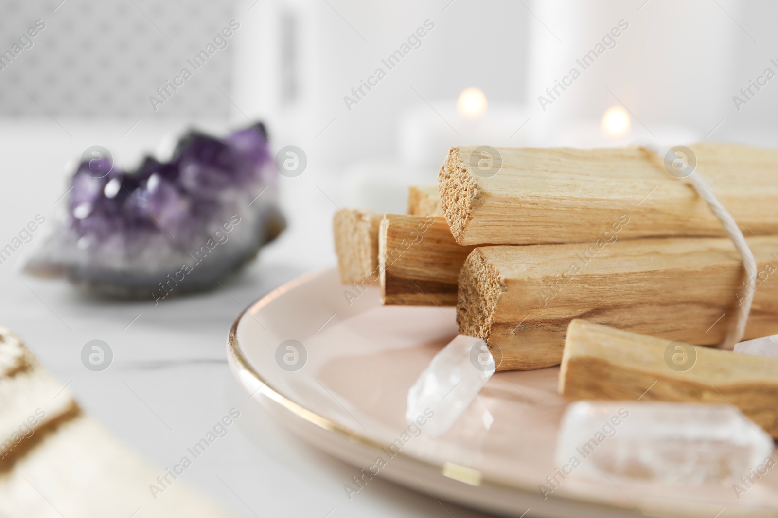 Photo of Palo santo sticks and gemstones on white table, closeup