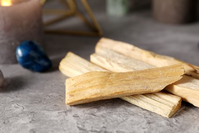 Photo of Palo santo sticks and gemstones on grey table, closeup