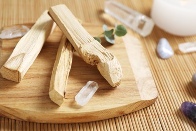 Photo of Palo santo sticks and gemstones on wicker table, closeup