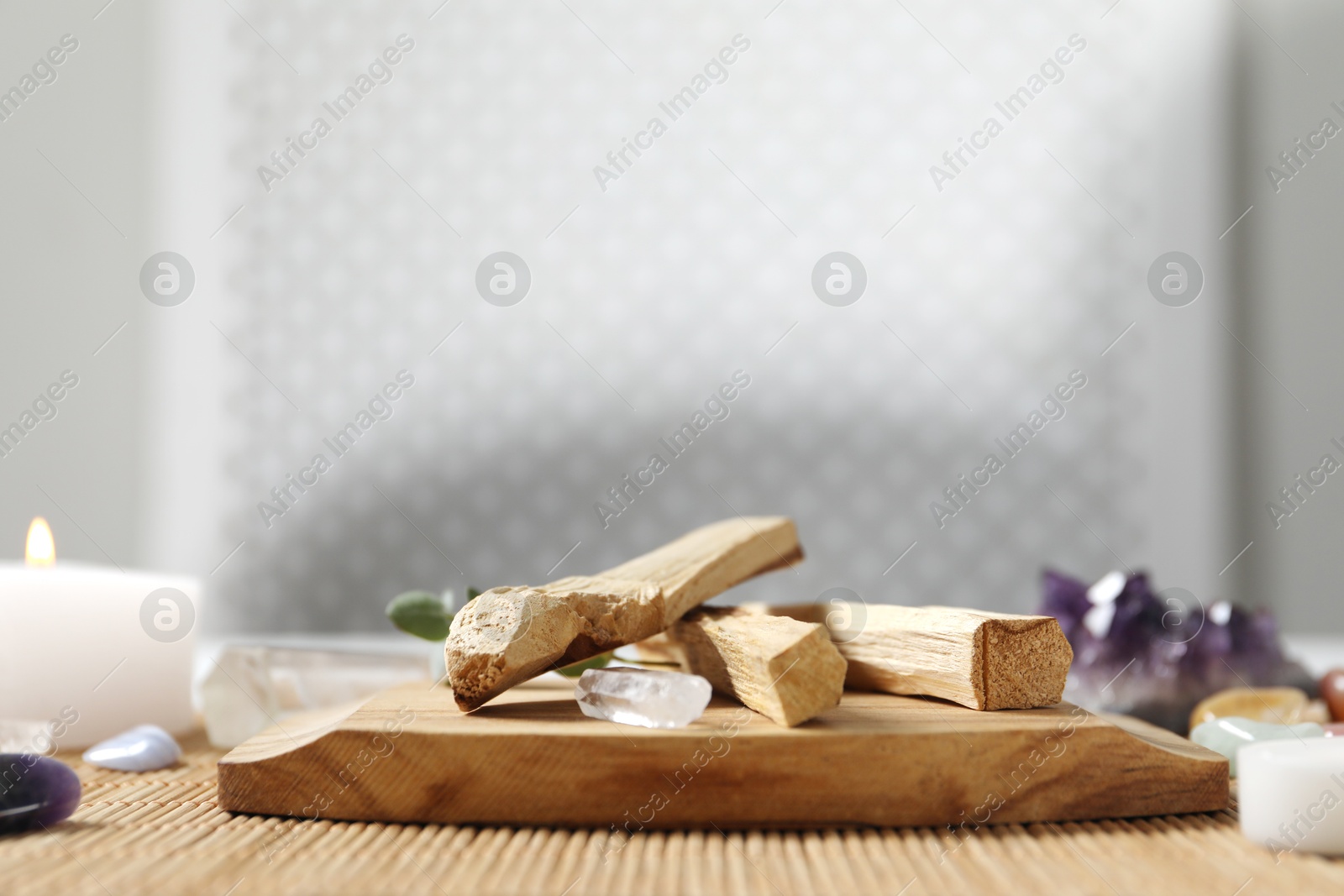 Photo of Palo santo sticks and gemstones on wicker table. Space for text