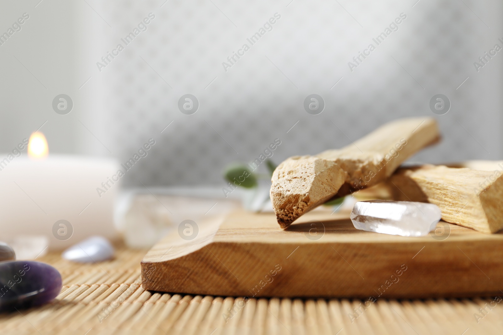 Photo of Palo santo sticks and gemstones on wicker table, closeup. Space for text