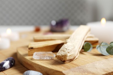 Photo of Palo santo sticks and gemstones on wicker table, closeup