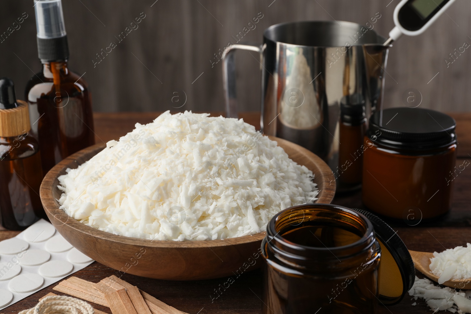 Photo of Soy wax and other supplies for making candles on wooden table, closeup