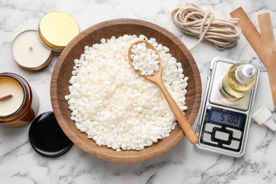 Photo of Soy wax and other supplies for making candles on white marble table, flat lay