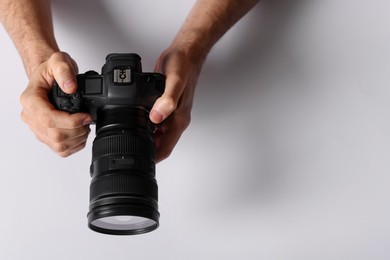 Photo of Photographer with professional camera on light background, above view. Space for text