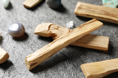 Photo of Palo santo sticks and gemstones on grey table, closeup