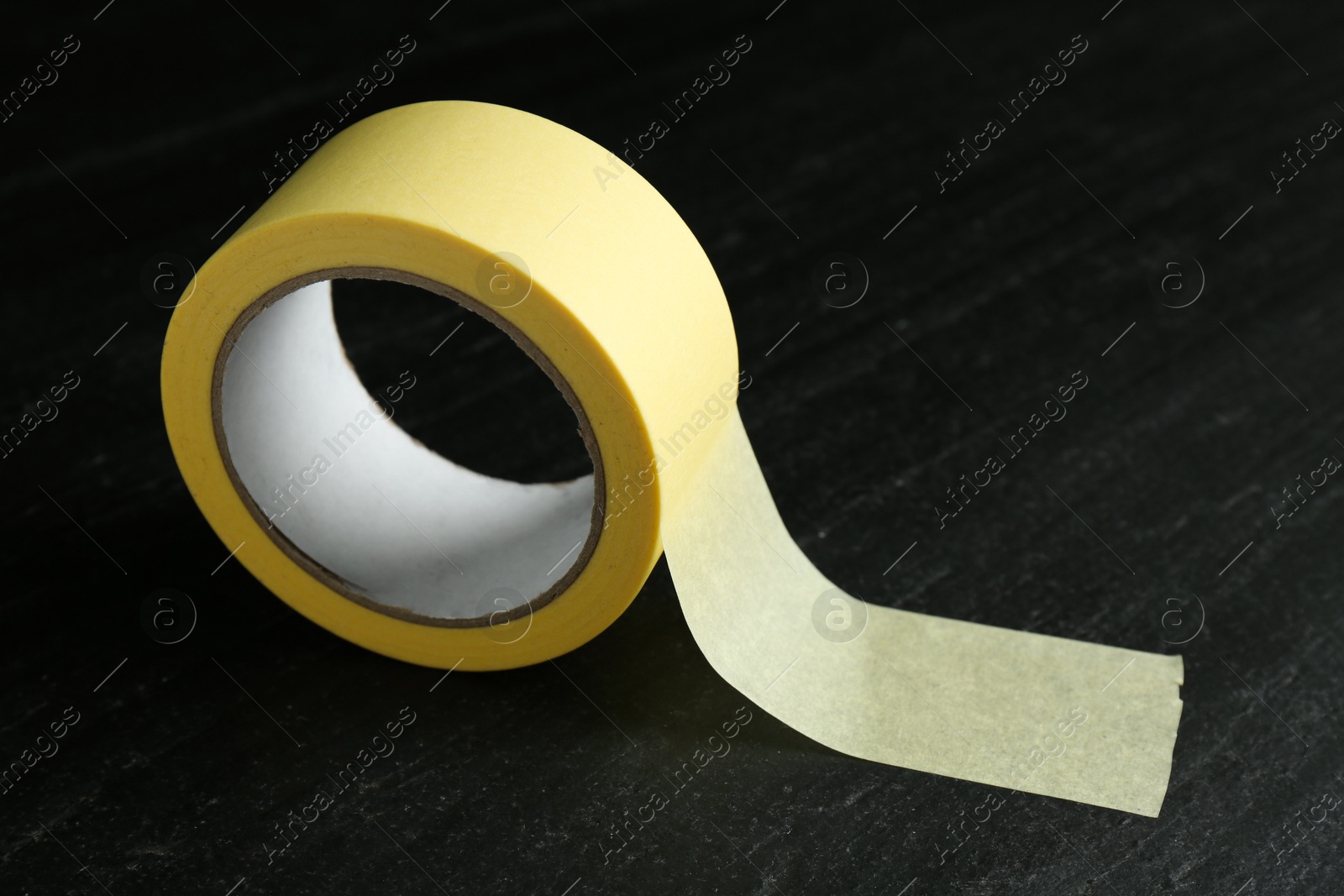 Photo of Roll of masking tape on black table, closeup