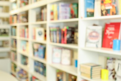 Photo of Bookcase with books in public library, blurred view