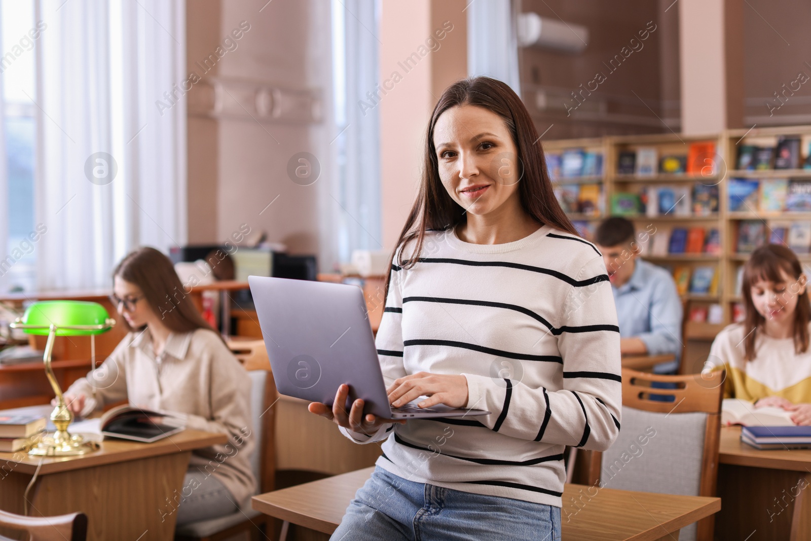 Photo of Portrait of smiling woman with laptop in library