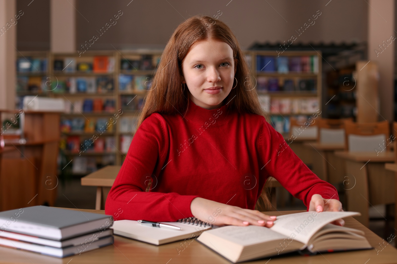 Photo of Girl reading book at desk in public library