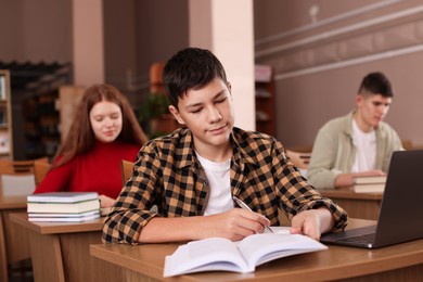 Photo of Boy taking notes at desk in public library